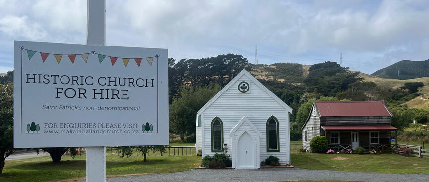 A sign outside a white wooden church reads 'Historic Church for hire. Saint Patrickʼs non-denominational.'