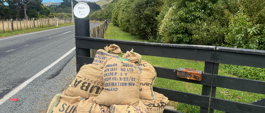 A hand drawn sign on a frisbee above a pile of hessian sacks.
