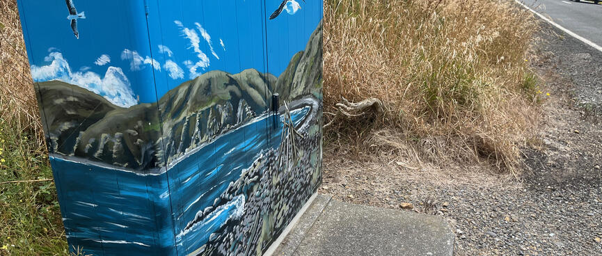 Rocky beaches, hills, sea and seagulls painted on a roadside power box.