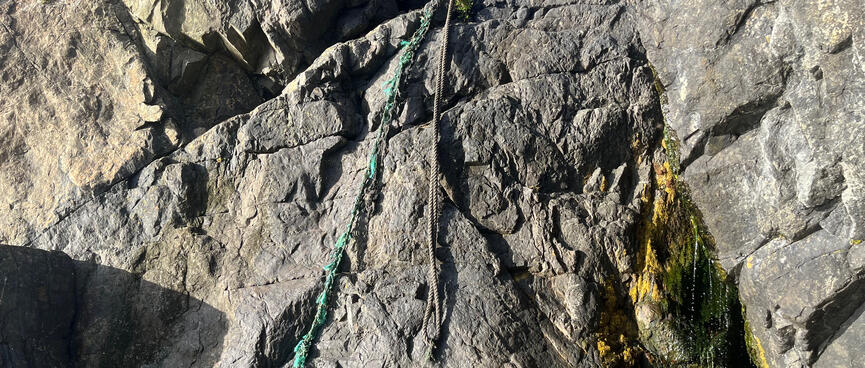 Two ropes hang down the face of a wide sloping rock.