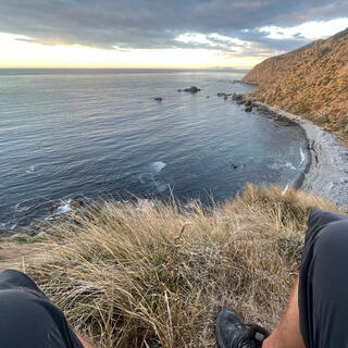 I sit on the tussock hillside, the beach and gravel sea stretch out below.
