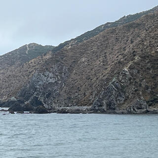 A section of coastline shows two rock ribs which block the beach, with steep hillsides around them.