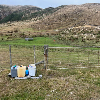 Plastic containers lined up next to a farm gate.