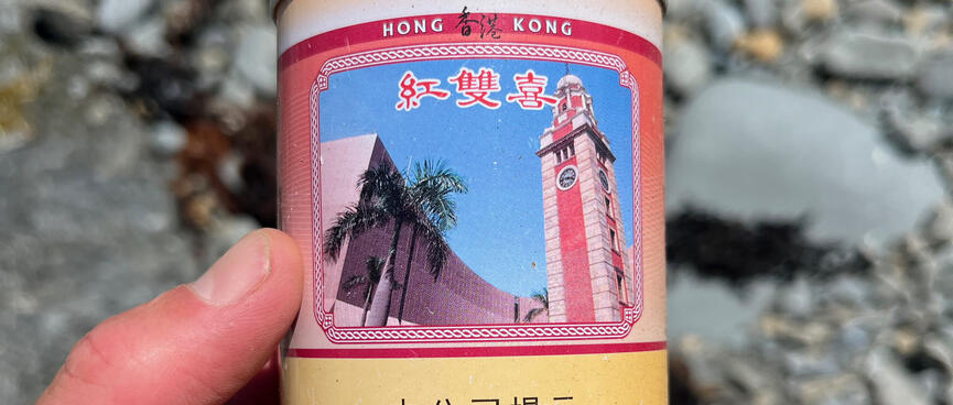 An empty can with some Chinese text, the words ʼHong Kongʼ and a picture of a clock tower.