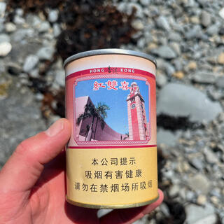 An empty can with some Chinese text, the words ʼHong Kongʼ and a picture of a clock tower.