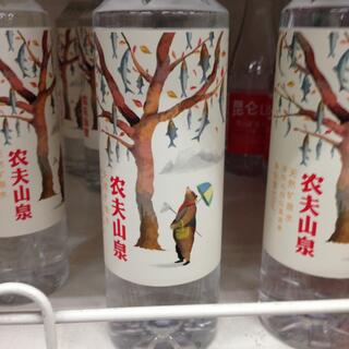 A bear with a fishing net gazes up at a tree of fish, on a water bottle label.
