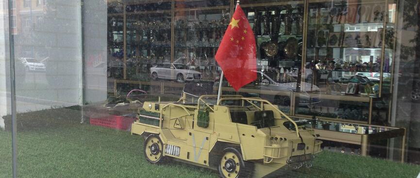 A scale model Armoured Personnel Vehicle is the size of a large cat and flies the Chinese flag.