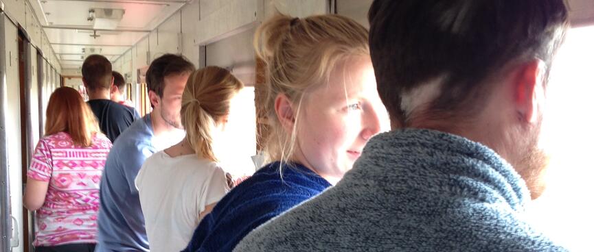 Train passengers discuss the view while standing in the aisle of a carriage.