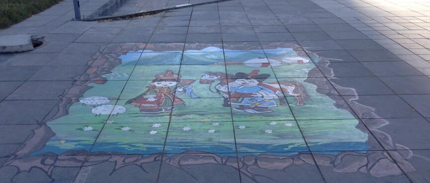 A chalk drawing on the footpath depicts women in traditional dress.
