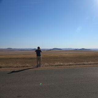 A man photographs steppes and distant hills.