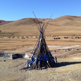 A large teepee of branches is secured with blue ribbon.