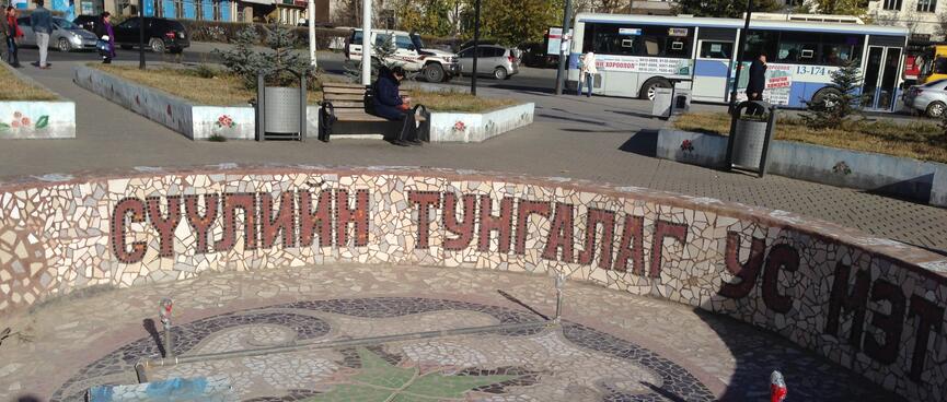 A tiled pond features the Cyrillic text ʼСУУЛИЙН ТУНГАЛАГ УС МЗТʼ.