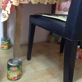Four cans of Del Monte Tropical Fruit Mix elevate my small wooden desk.