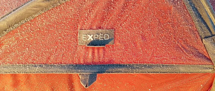 Frozen snow surrounds the EXPED logo on a panel of my tent.