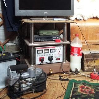 A solar battery meter with Chinese labels sits below a VCR and a widescreen TV.