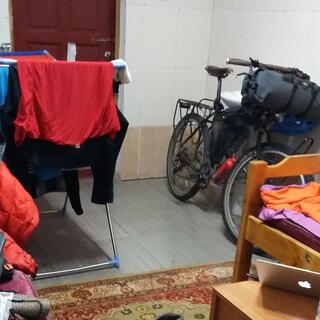 Clothes on a drying rack and my other belongings scattered around a tiled room.
