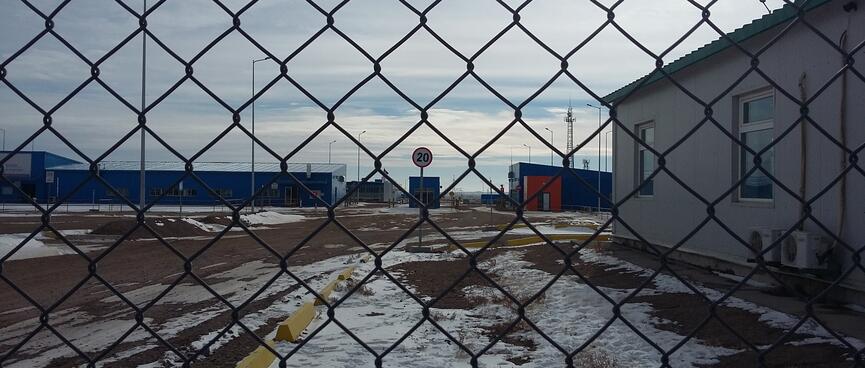 Mine compound viewed through a chain link fence.