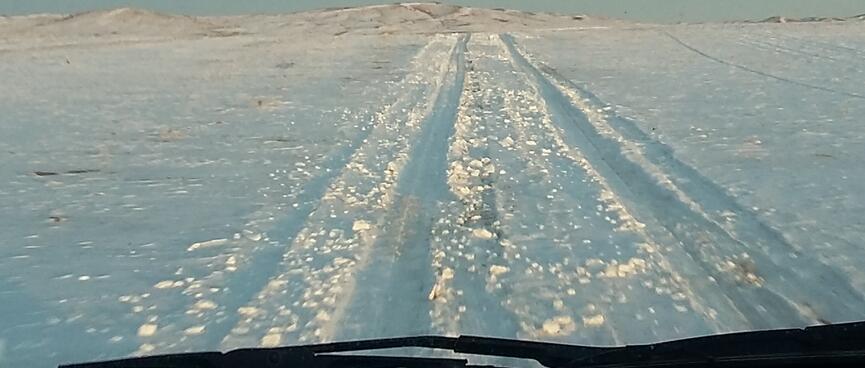View out the windscreen to tyre tracks through the snow.