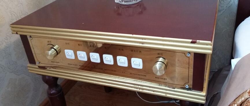 The front panel of a bedside table features six switches and two dials.