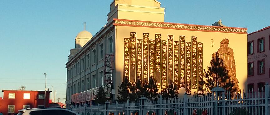 Vertical strips of text on the side of a square building with twin domed towers.