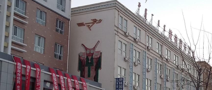 The side of a building features a stylized figure wearing a cloak and a horned mask.