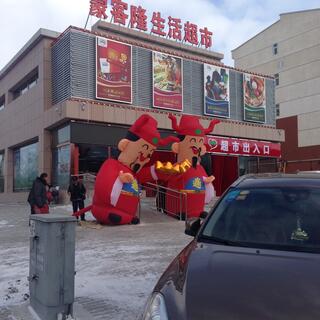Two giant wind-battered Ming figures outside a supermarket.
