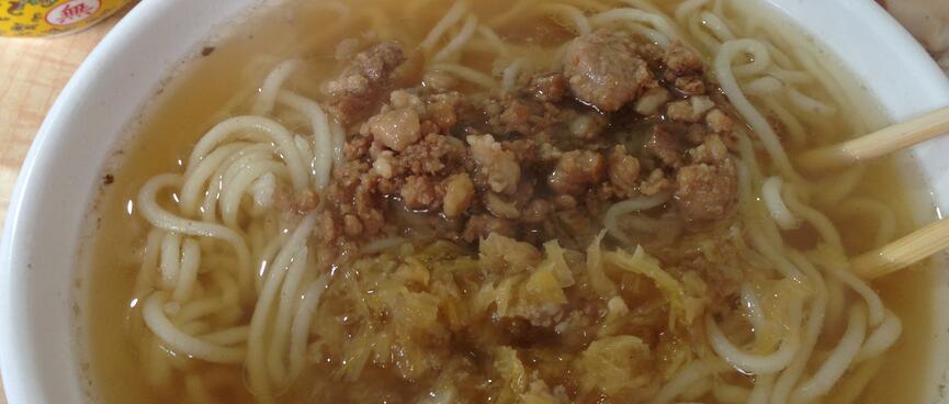 A cluster of meat chunks surrounded by thin noodles and clear yellow broth.