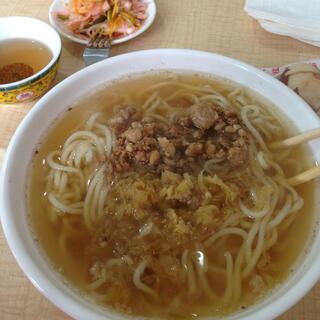 A cluster of meat chunks surrounded by thin noodles and clear yellow broth.