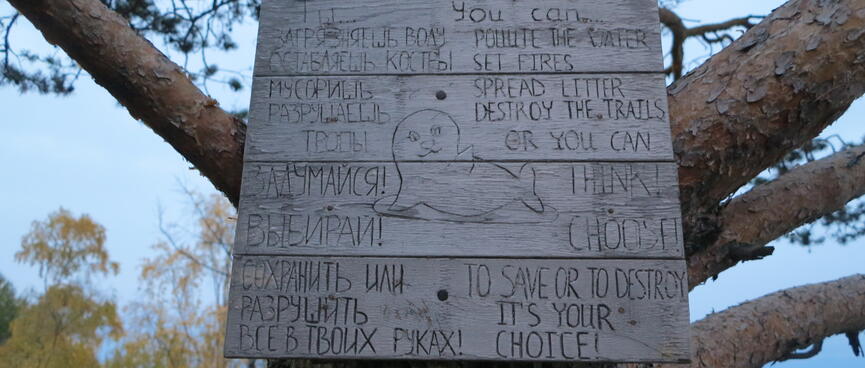 A wooden sign implores campers to take care of their surroundings.