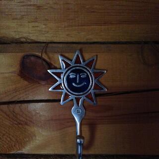 A metal coat hook adorned with a smiling sun.