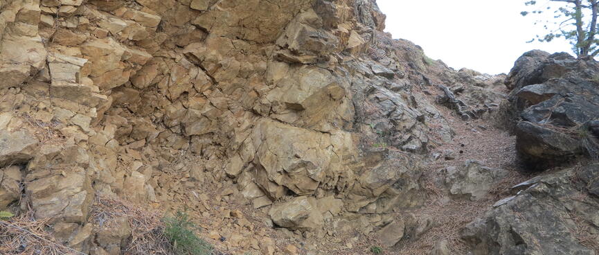 A trailside rock face splinters into small rocks.