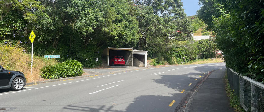 A surburban street with garages and a street sign.