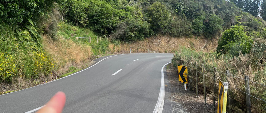 Pointing to a safe crossing point just before the corner.