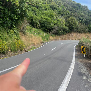 Pointing to a safe crossing point just before the corner.
