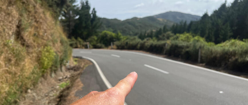 Pointing to a safe crossing point just before the next corner.