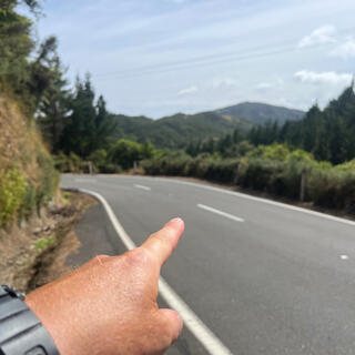 Pointing to a safe crossing point just before the next corner.