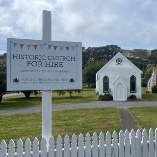 A sign outside a white wooden church reads 'Historic Church for hire. Saint Patrickʼs non-denominational.'