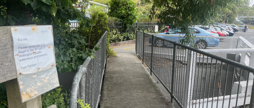 An A4 sign on the fence before a short pedestrian bridge.