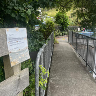 An A4 sign on the fence before a short pedestrian bridge.