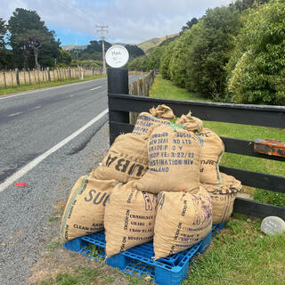 A hand drawn sign on a frisbee above a pile of hessian sacks.
