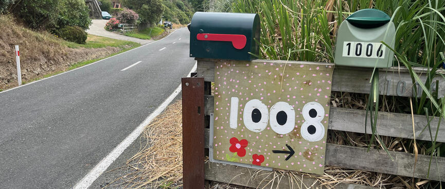A hand painted sign features a bold house number and cute red flowers.