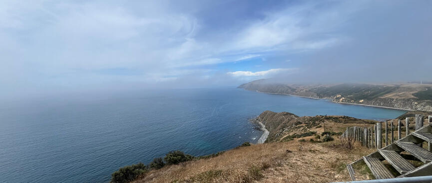 Grey mist partially covers the sea and hills.