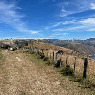 White three-bladed wind turbines cover the hills to the south.