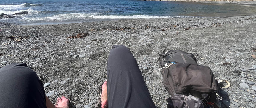 Sitting on the beach with wet shorts, my bare feet are covered in small pebbles.