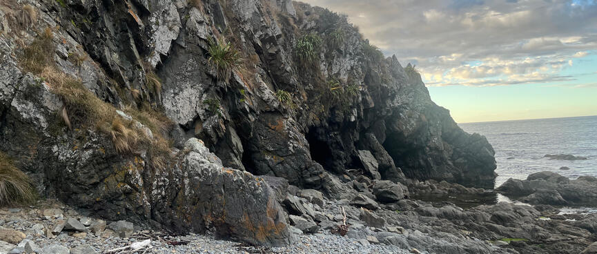 A rocky bank runs all the way down to the waterline, blocking the beach.