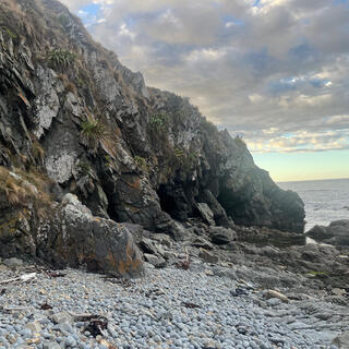 A rocky bank runs all the way down to the waterline, blocking the beach.