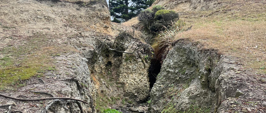 Water seeps through a hole in the land underneath the buildings.