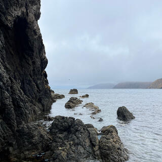 A rock face rises up from the sea.