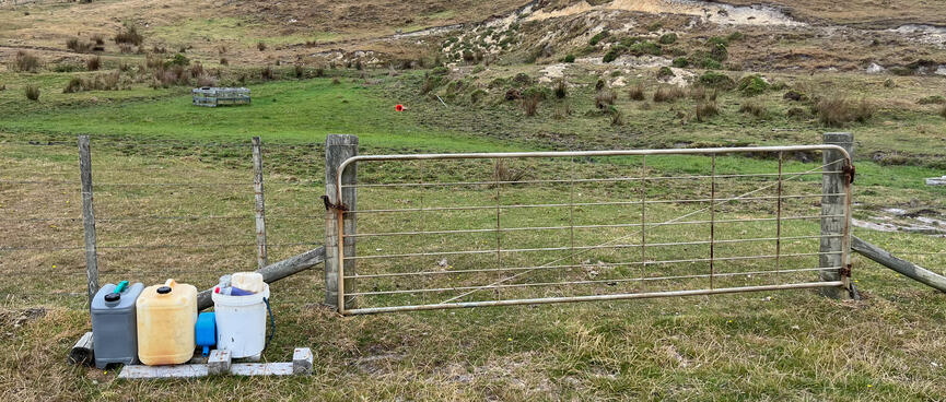Plastic containers lined up next to a farm gate.