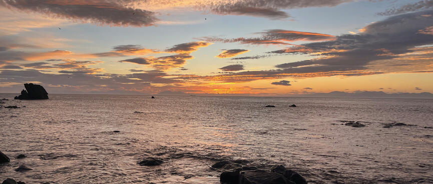 Apricot and grey mottled clouds above a darkened sea.